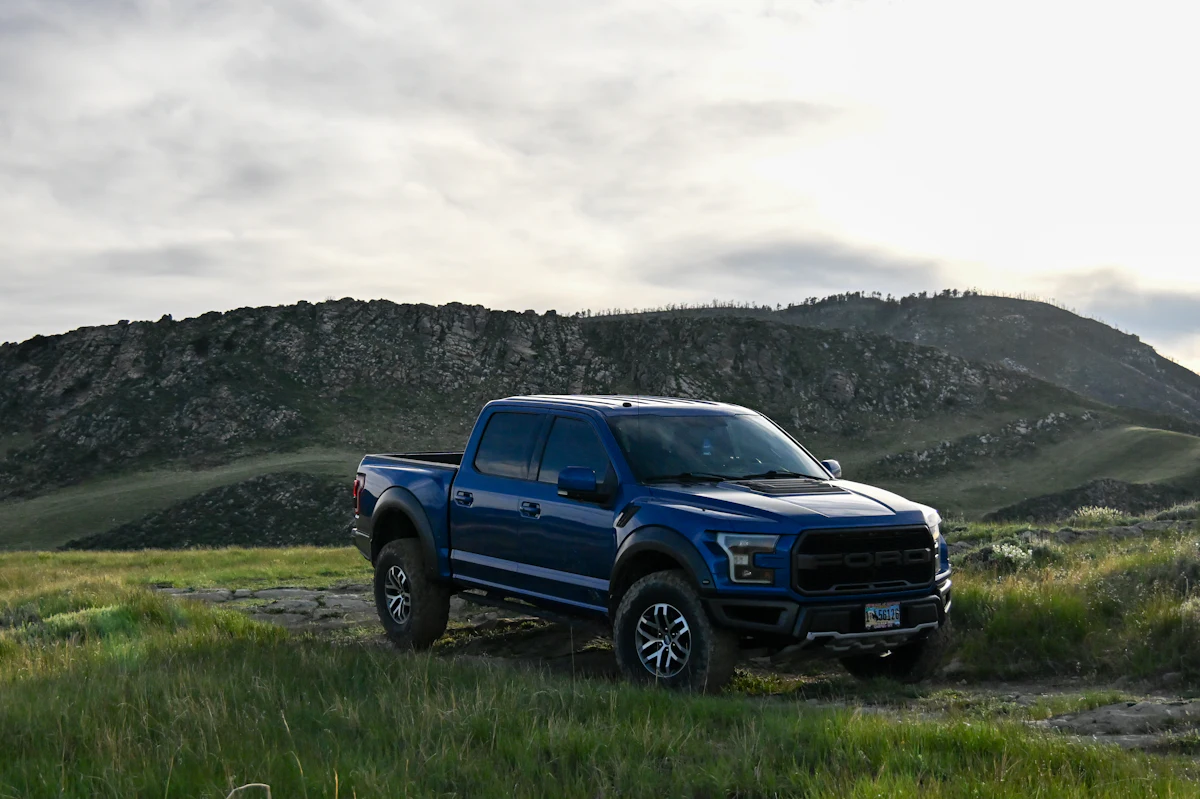 Blue Ford F-150 Raptor parked on grass