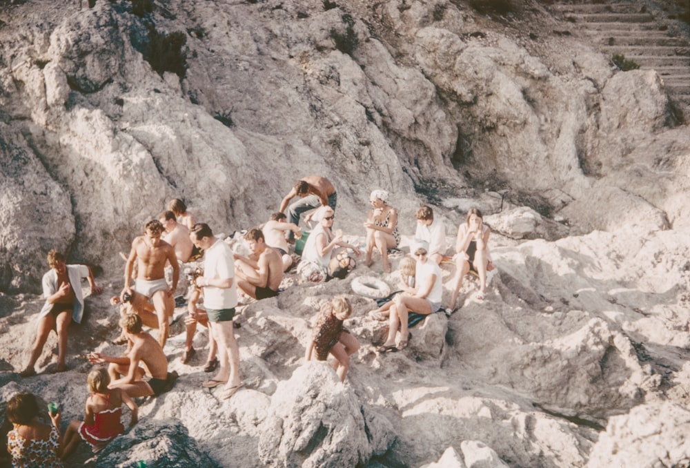 a group of people sitting on top of a rocky beach