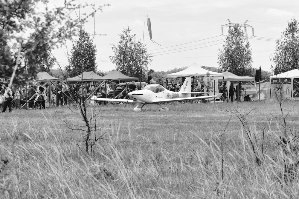 une photo en noir et blanc d’un petit avion dans un champ