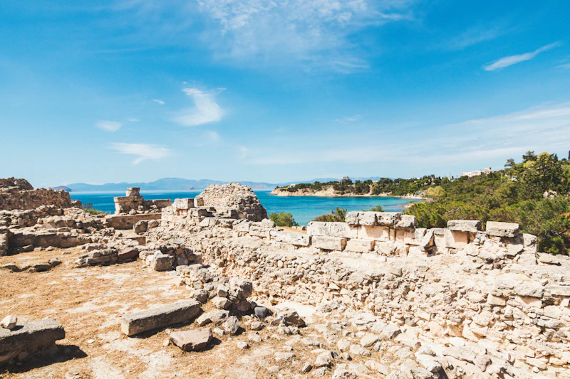 Ancient stone ruins on a headland above a blue bay
