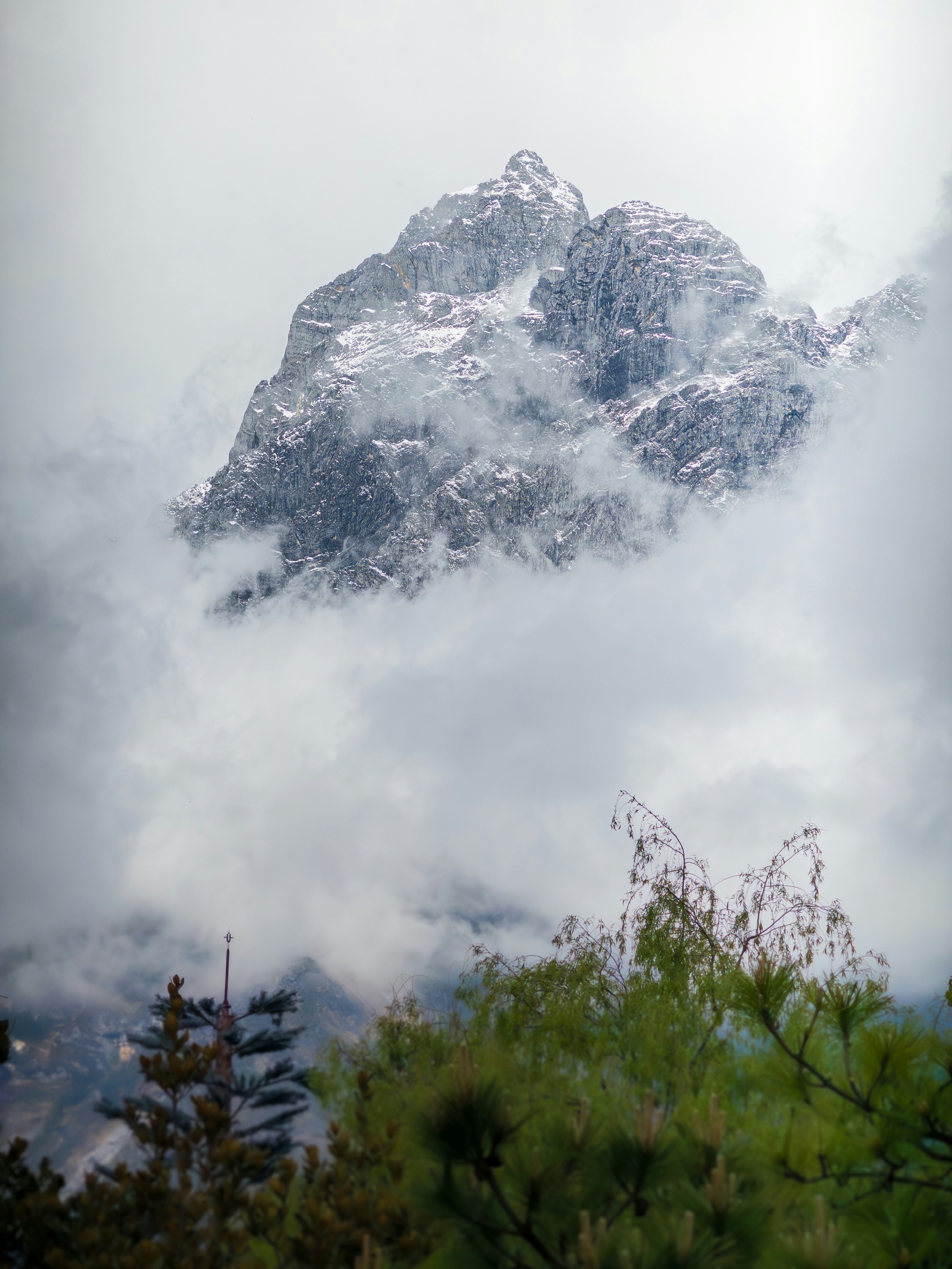 a mountain covered in snow surrounded by clouds