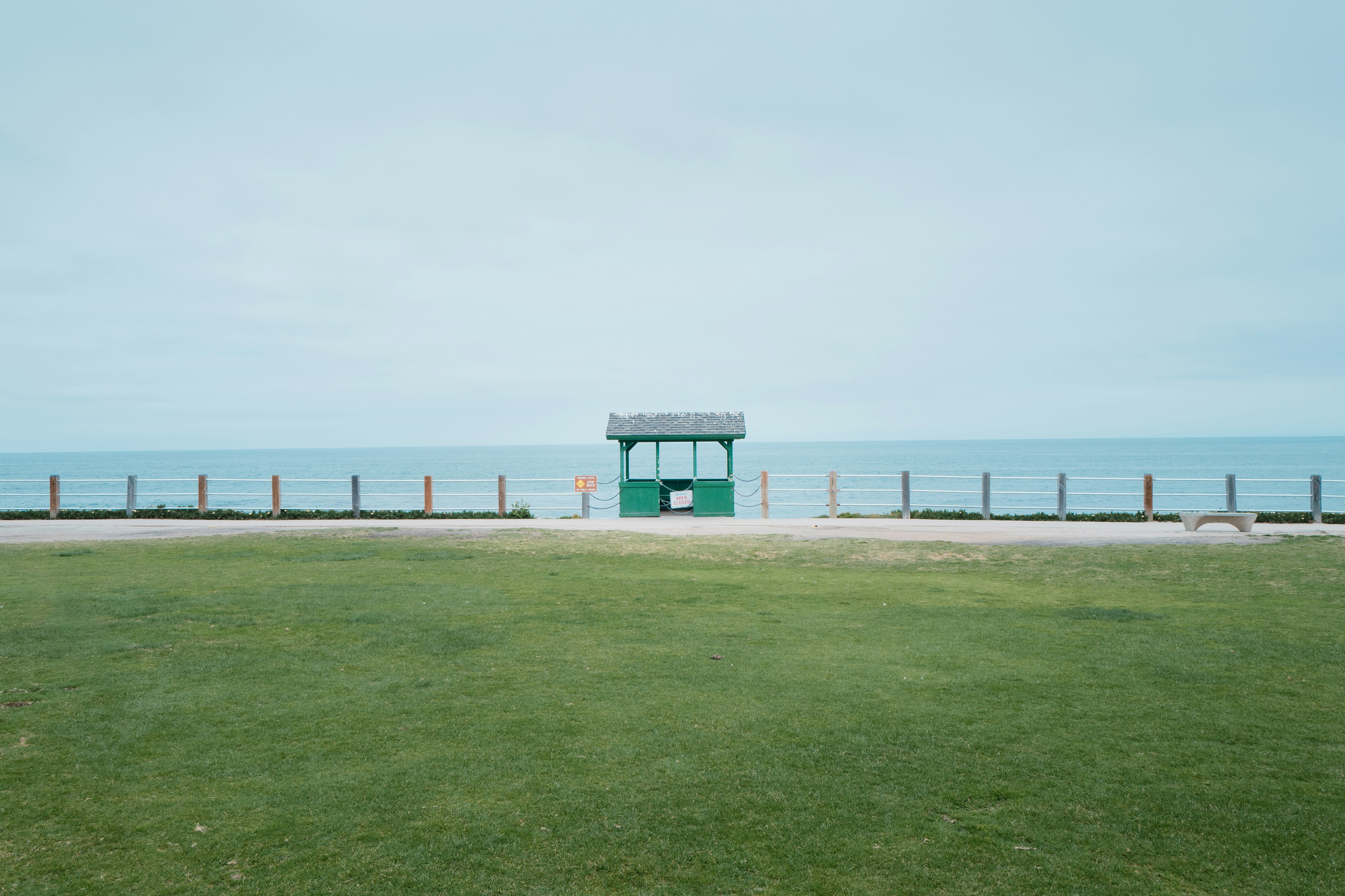 a grassy field with a small green structure in the middle of it