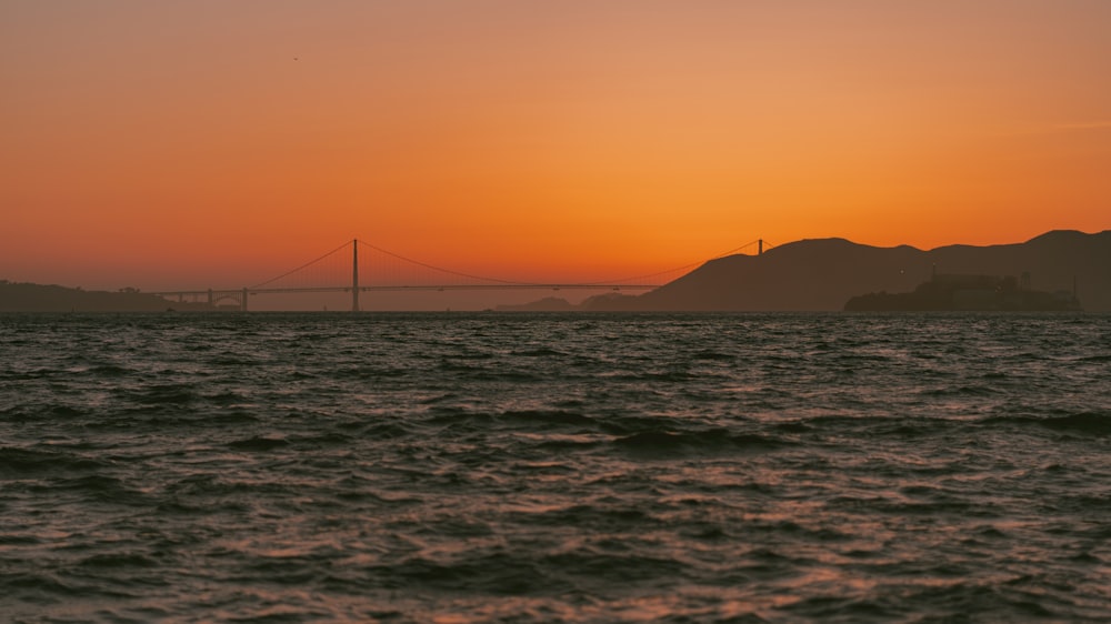 a large body of water with a bridge in the background