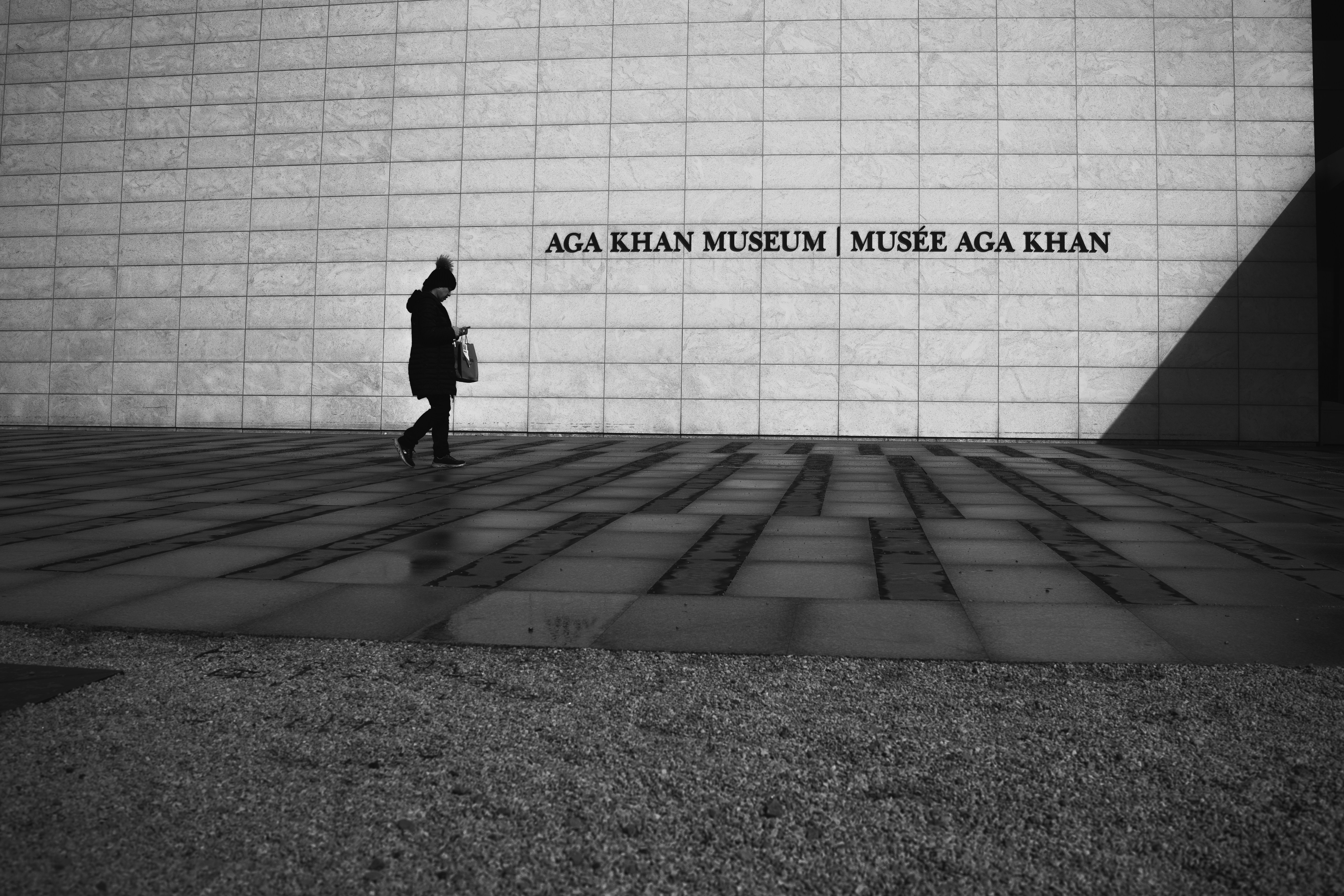 a woman walking past a wall with a quote on it