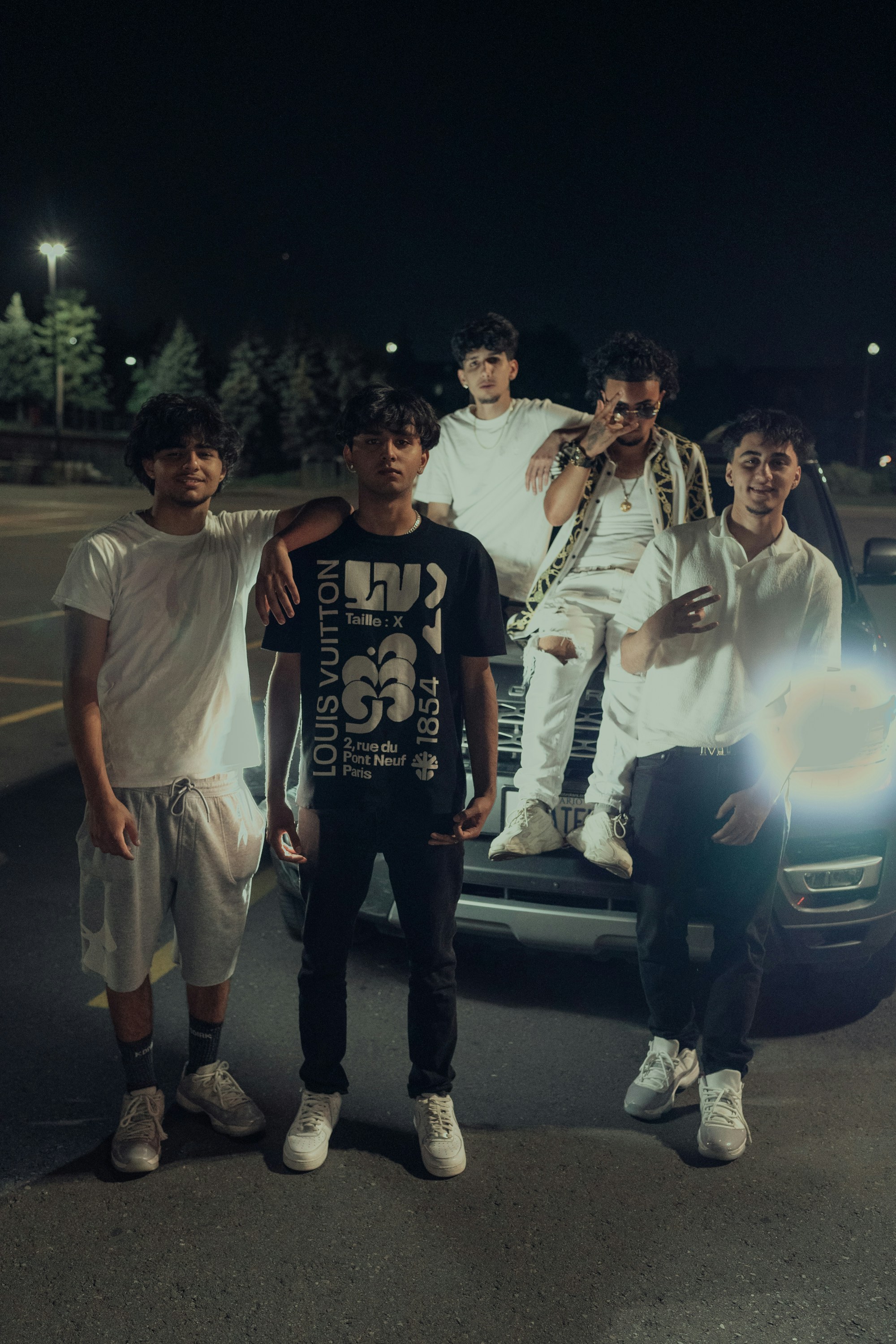 a group of young men standing next to a car