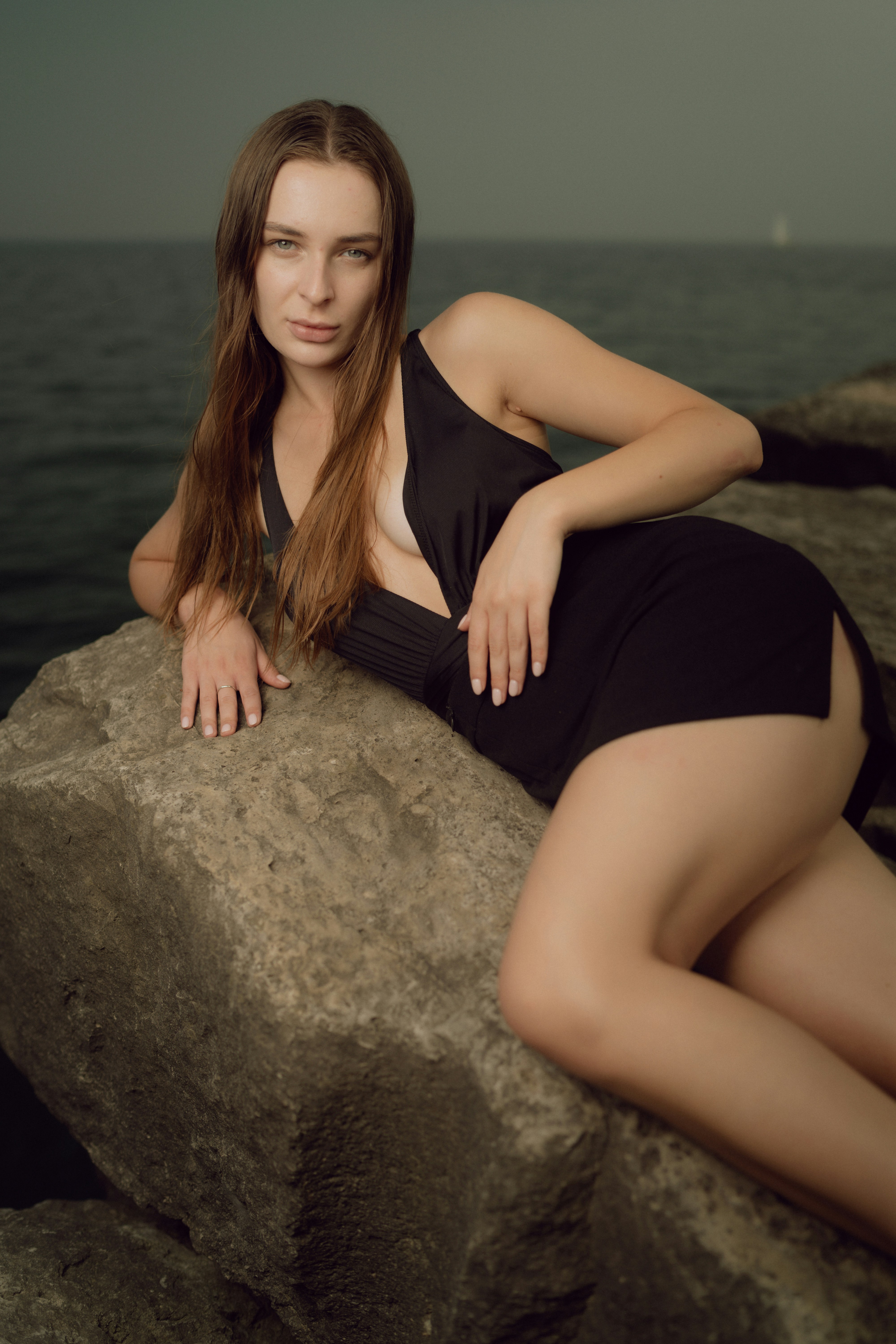 a woman in a black dress sitting on a rock
