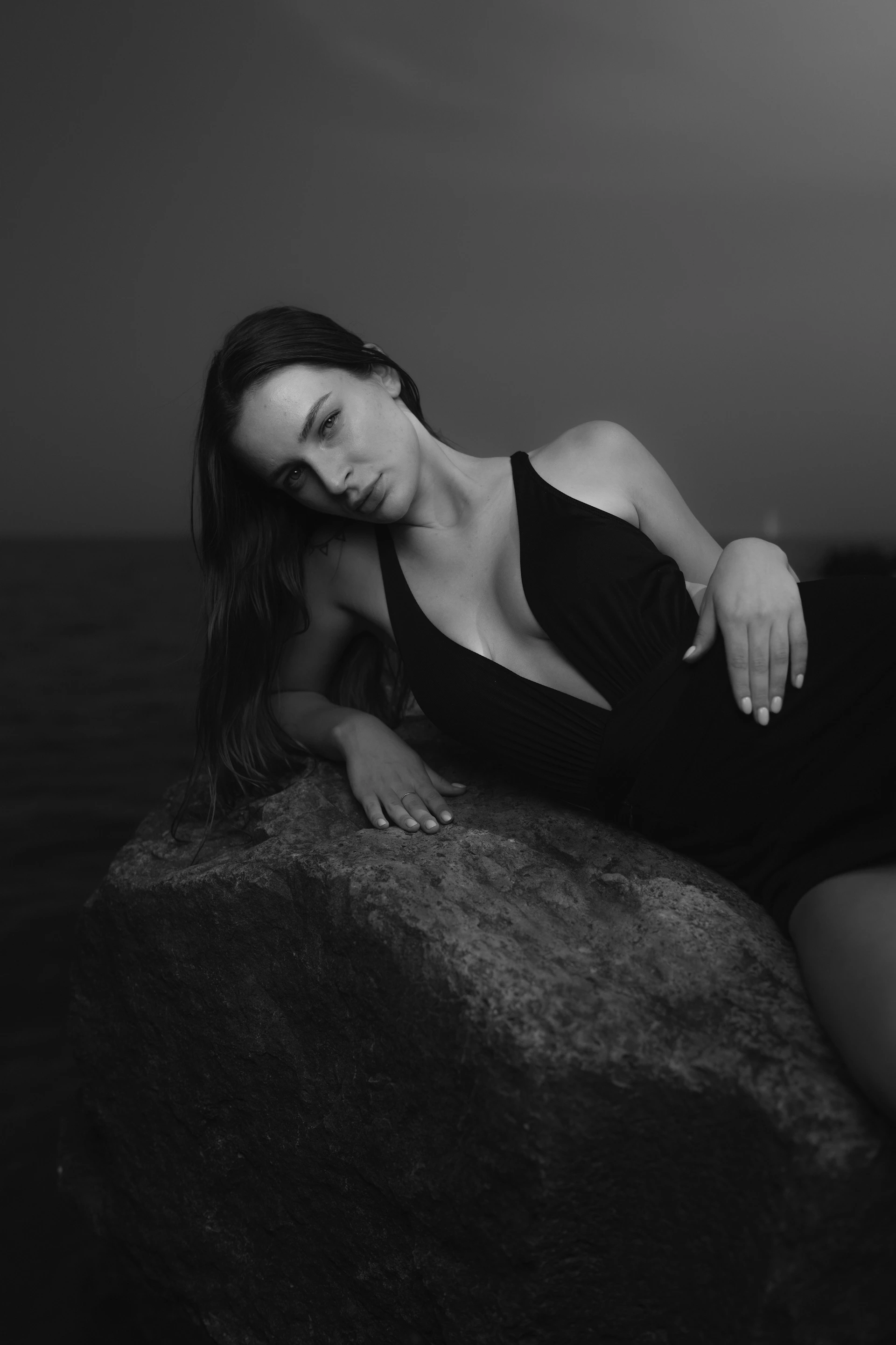 a woman sitting on top of a rock near the ocean