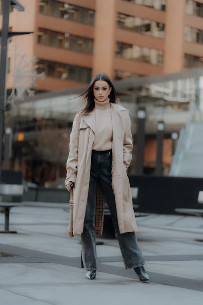 a woman in a trench coat is standing on the street