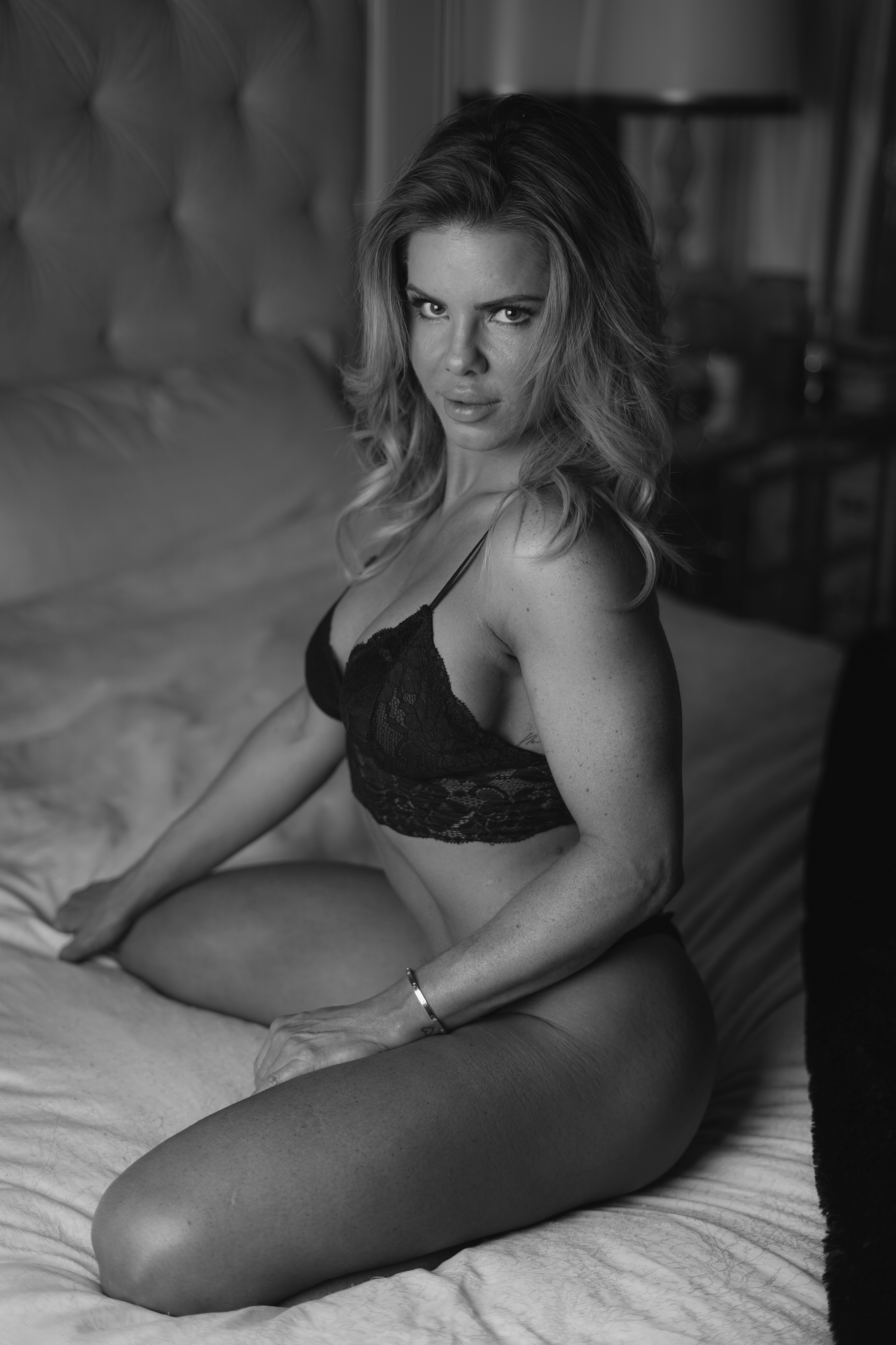 a woman sitting on a bed wearing a bra