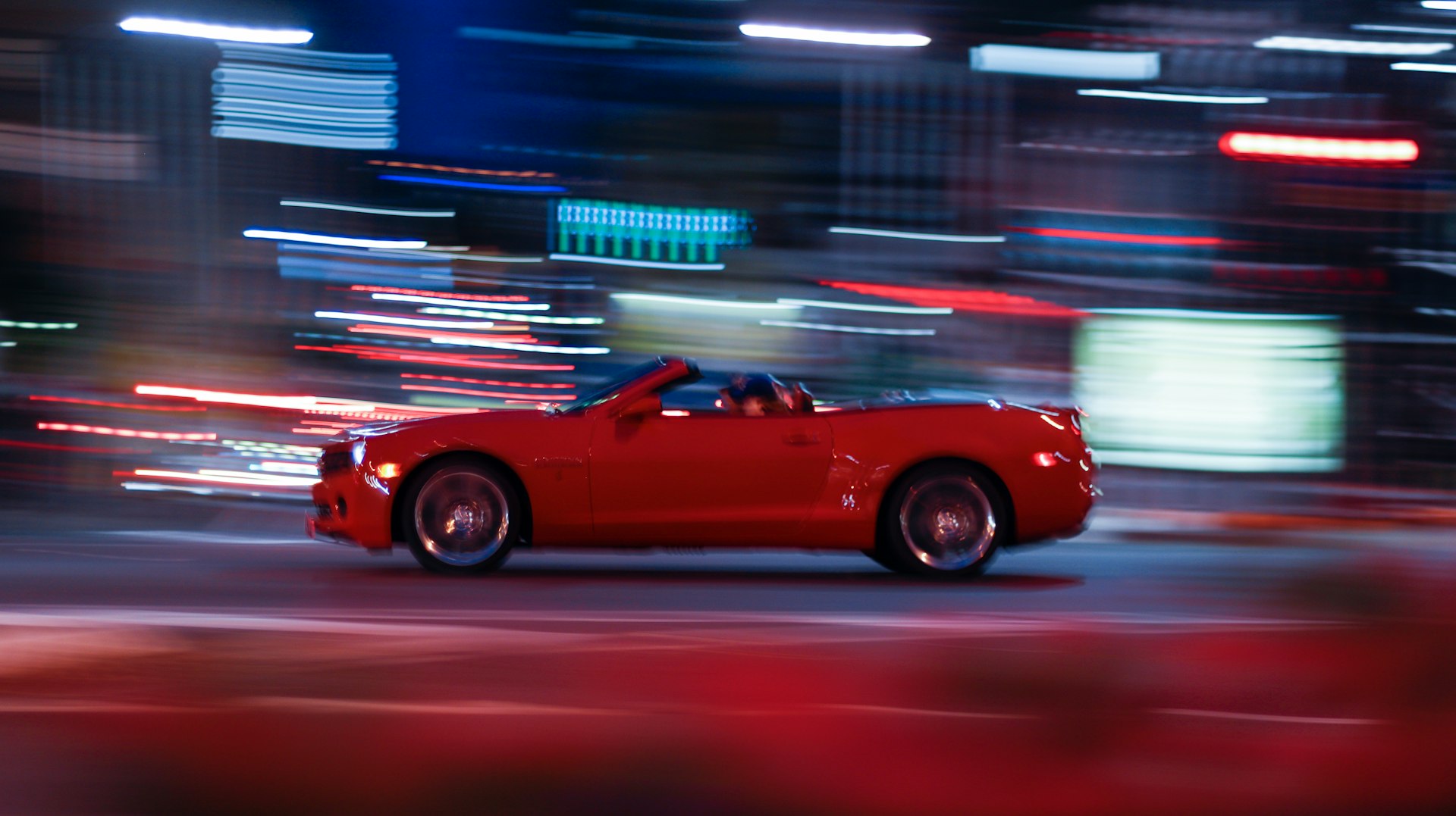 a red sports car driving down a city street