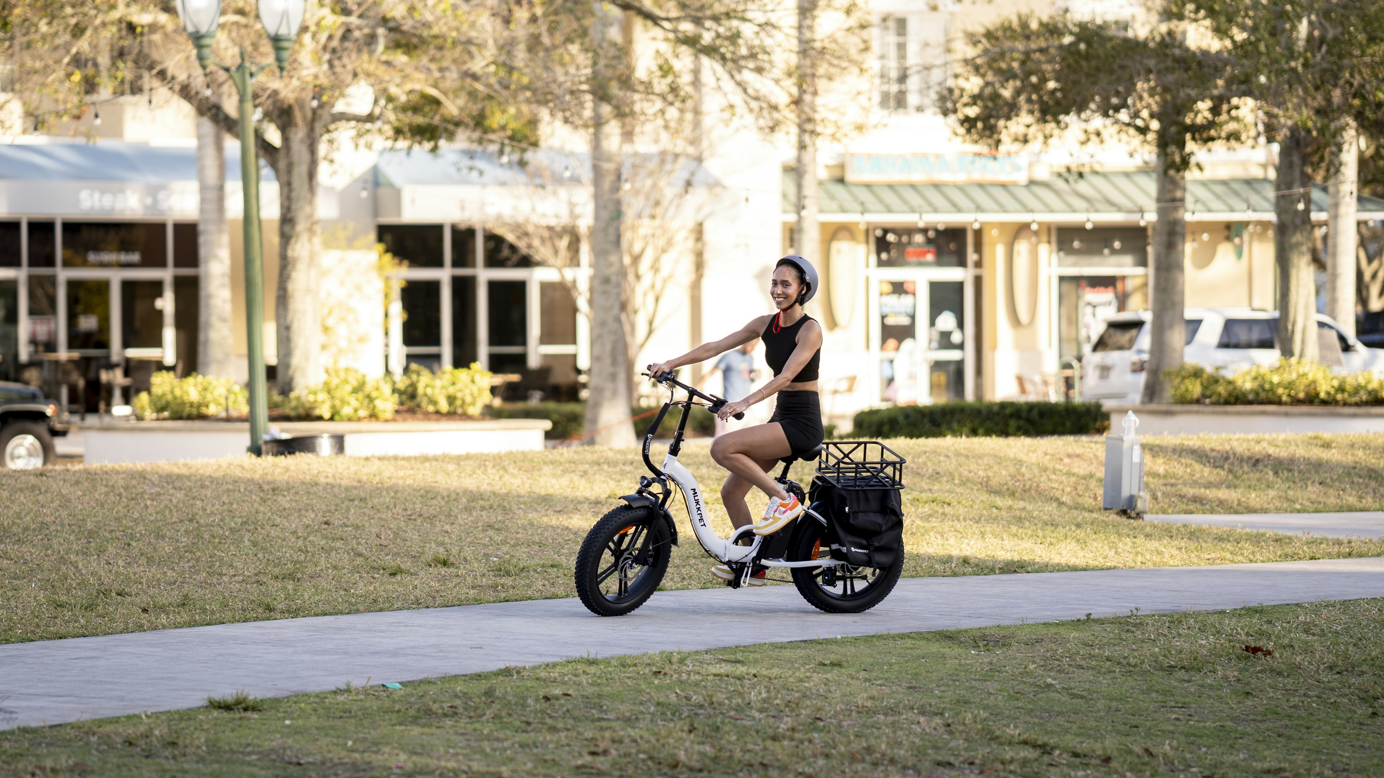 a woman riding a bike down a sidewalk