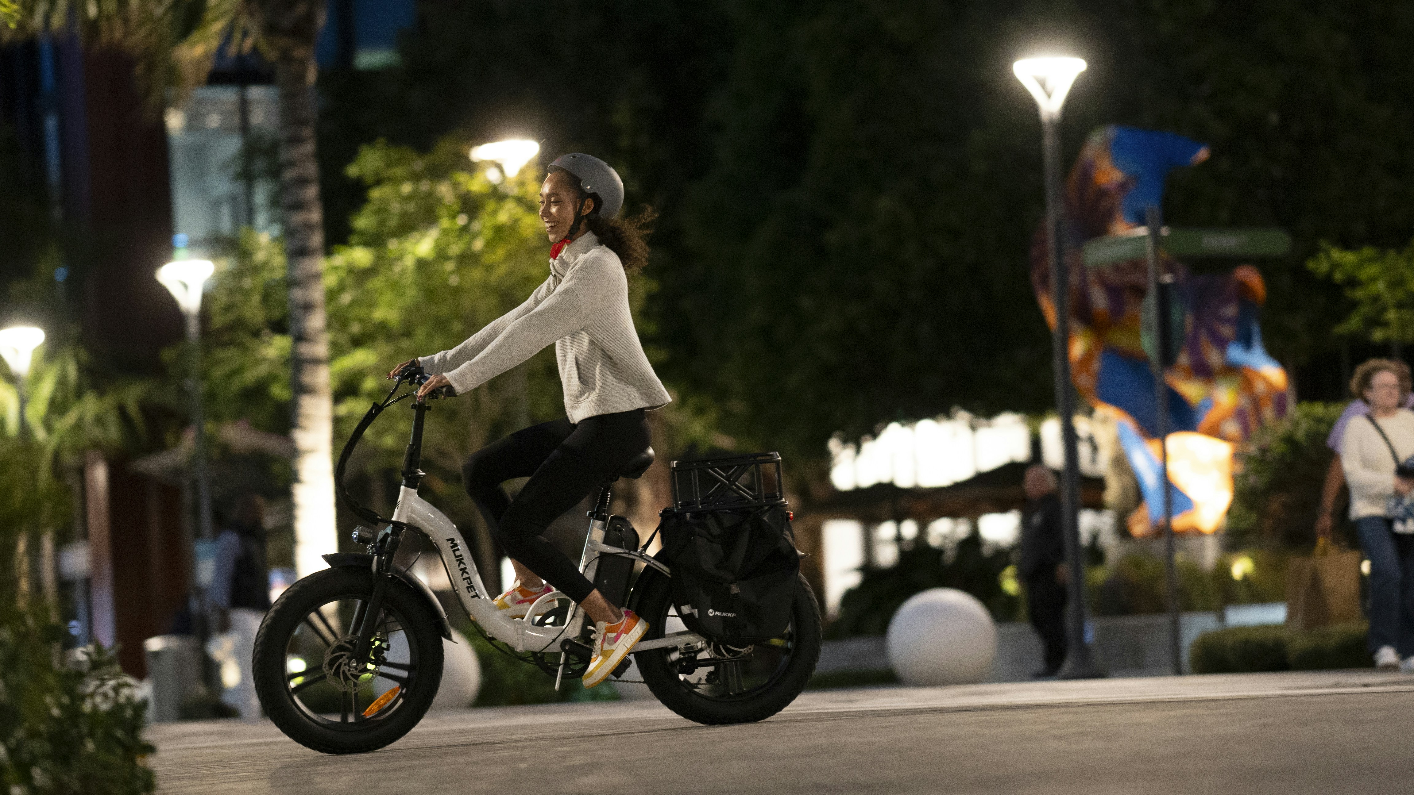 una mujer montando un scooter en una calle de la ciudad por la noche