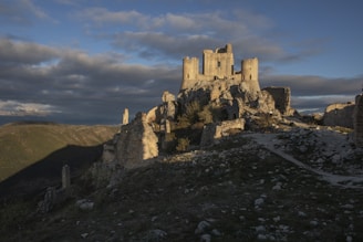 a castle sitting on top of a hill under a cloudy sky