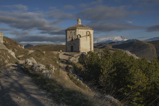 a small building on a hill with a sky background