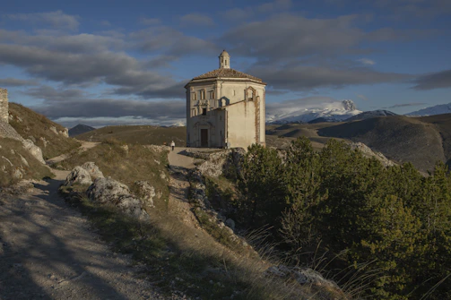 a small building on a hill with a sky background
