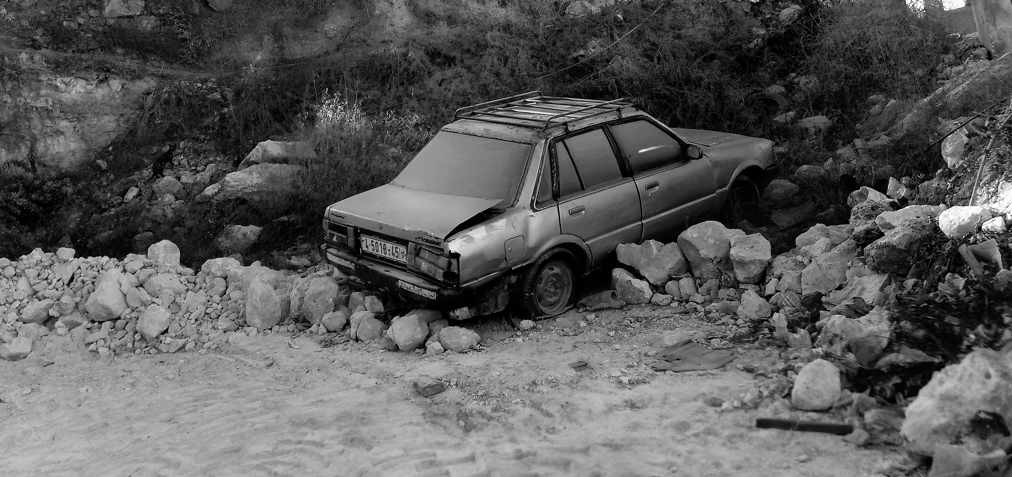 Black and white photograph of an old abandoned car. 