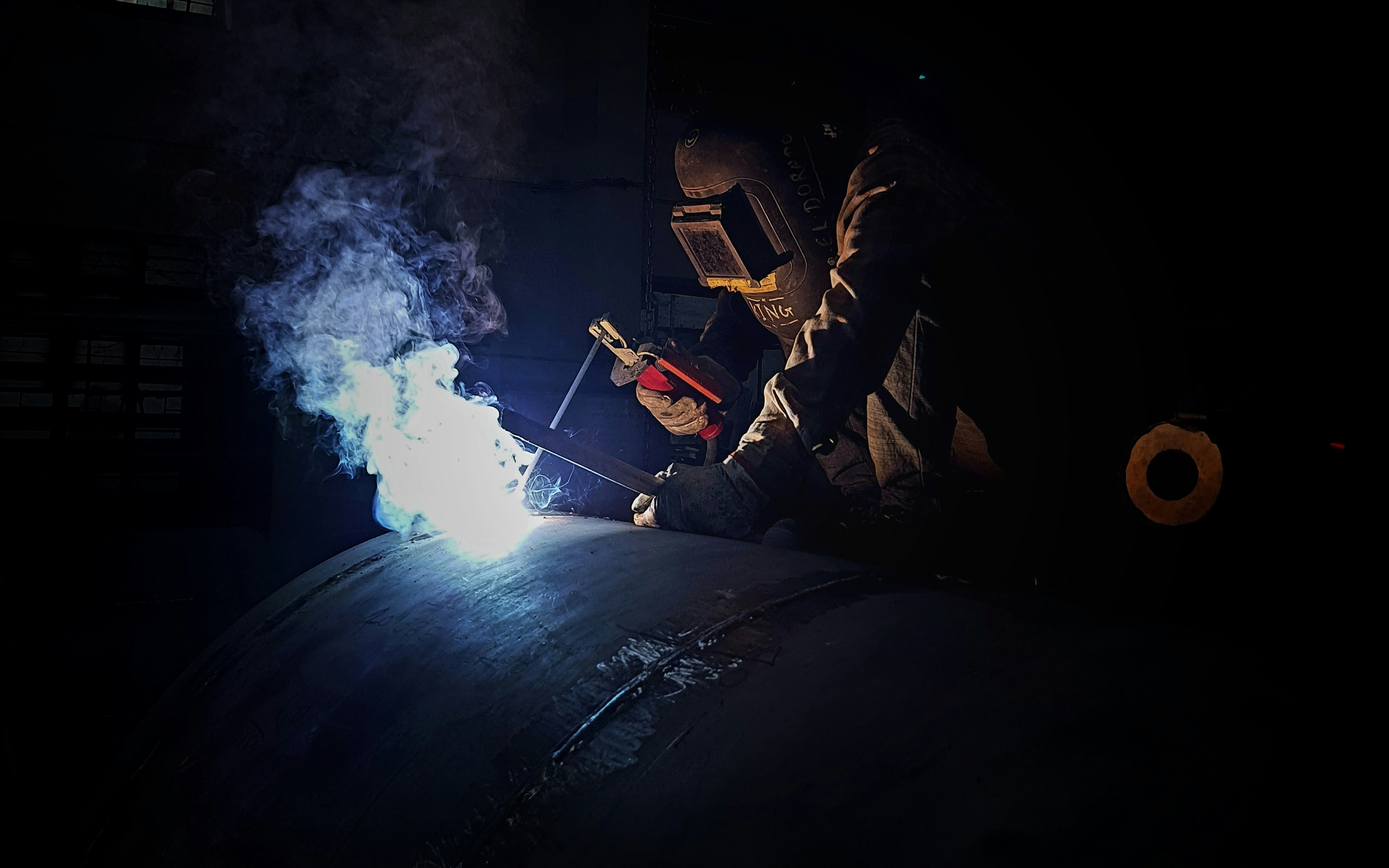 a welder working on a pipe in the dark