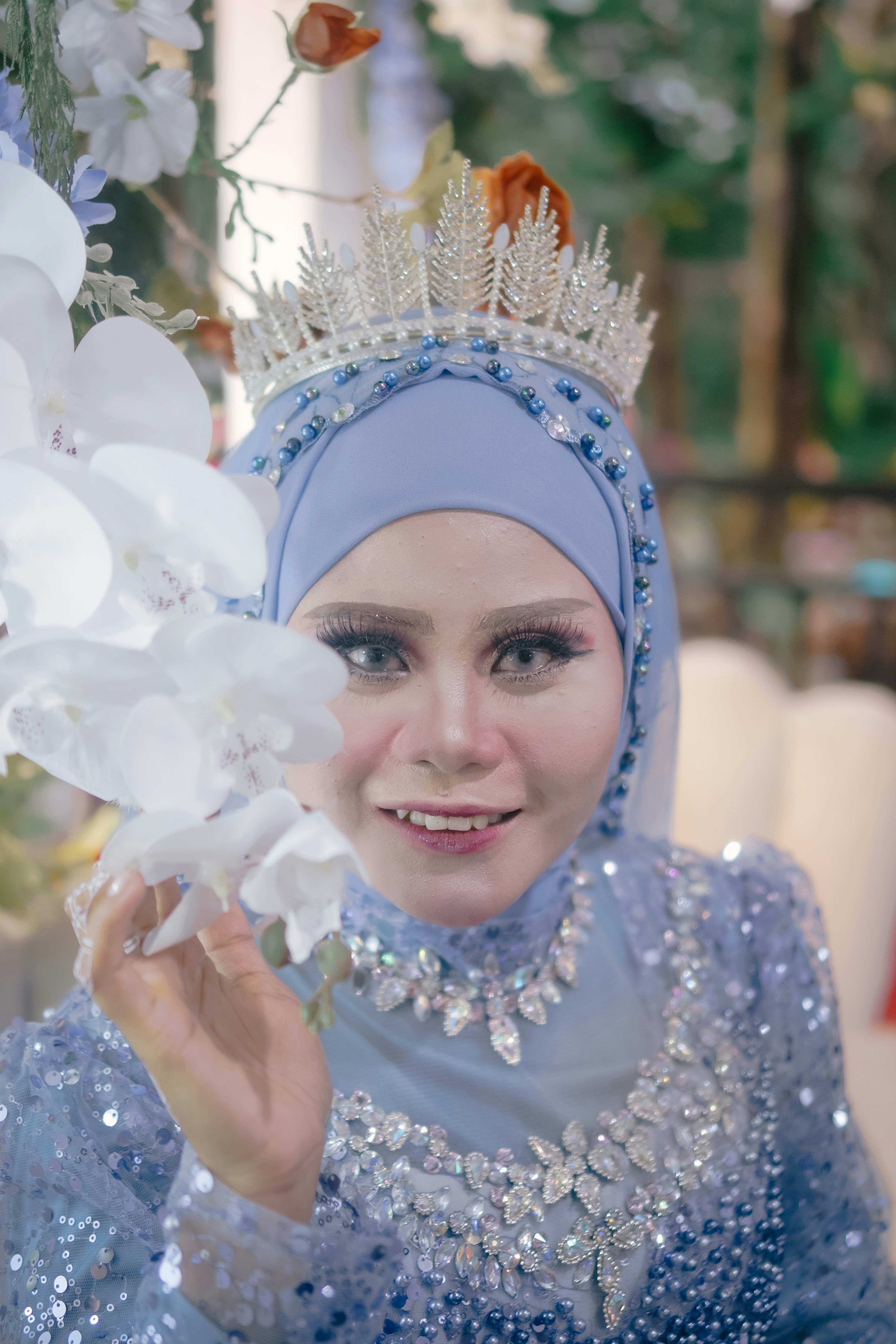 Seorang wanita bergaun biru memegang bunga