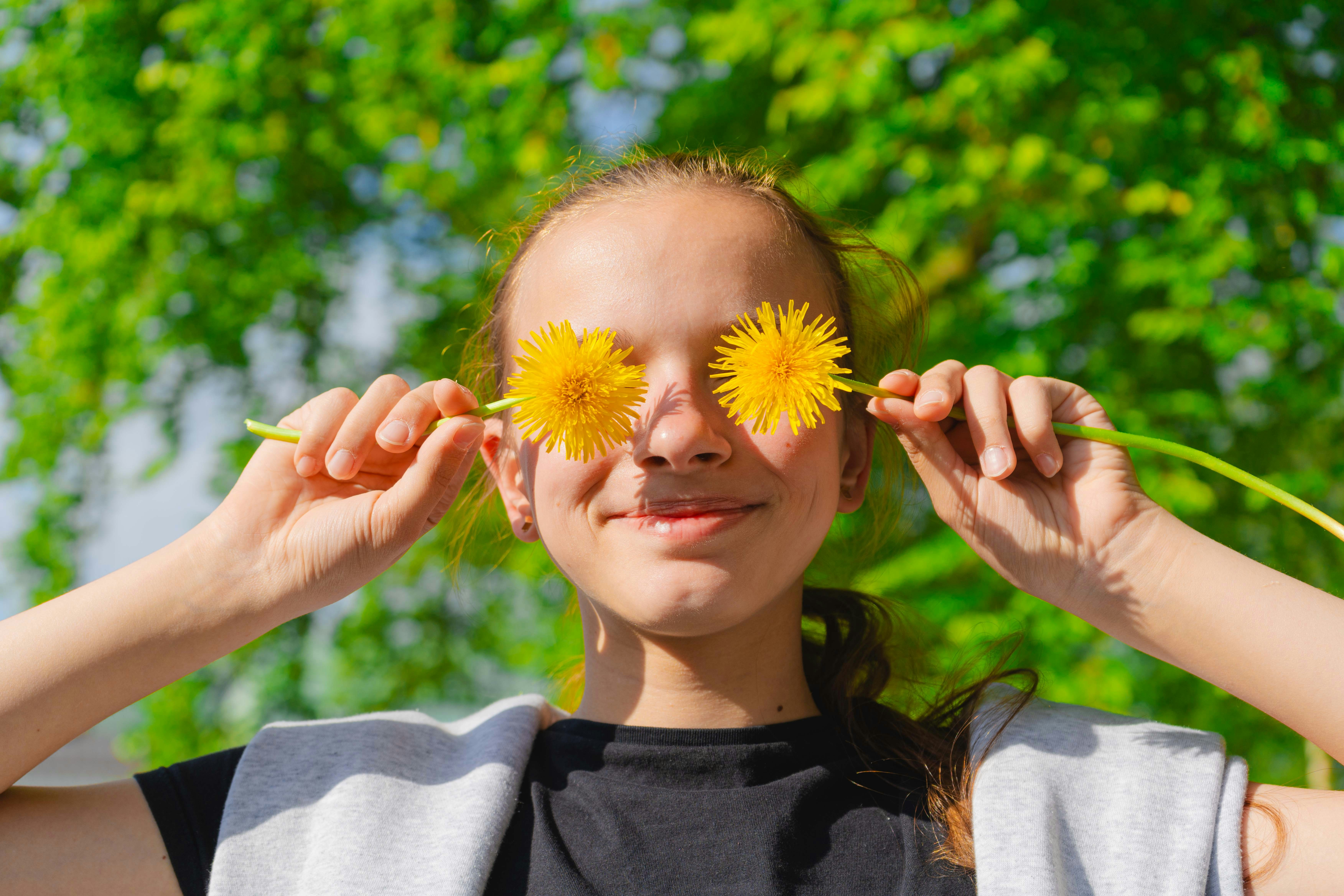 eine Frau, die zwei gelbe Blumen vor ihre Augen hält