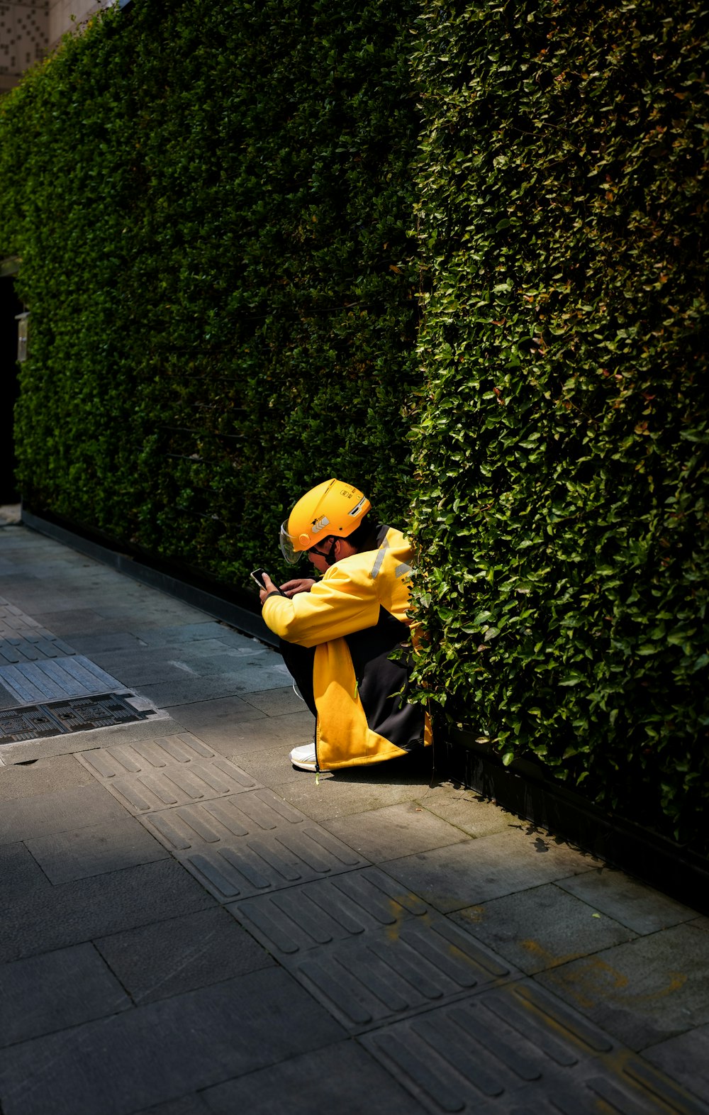 a person in a yellow hat leaning against a wall