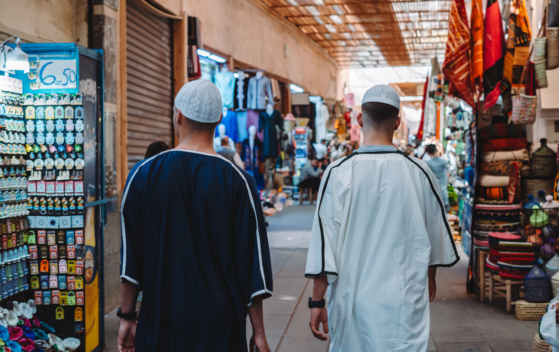 a couple of men walking down a street next to a store