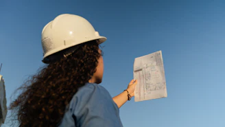 a woman wearing a hard hat holding a piece of paper