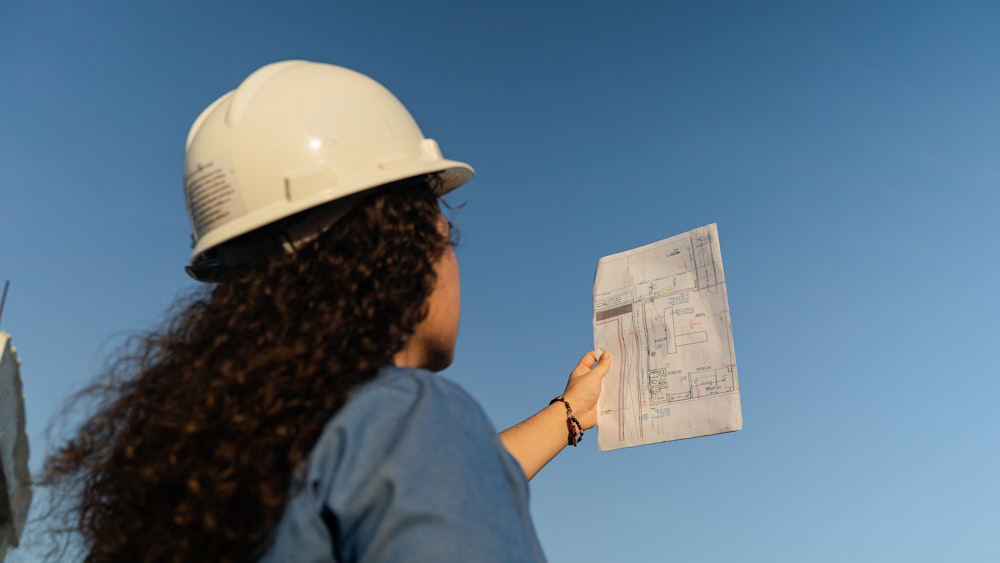 a woman wearing a hard hat holding a piece of paper