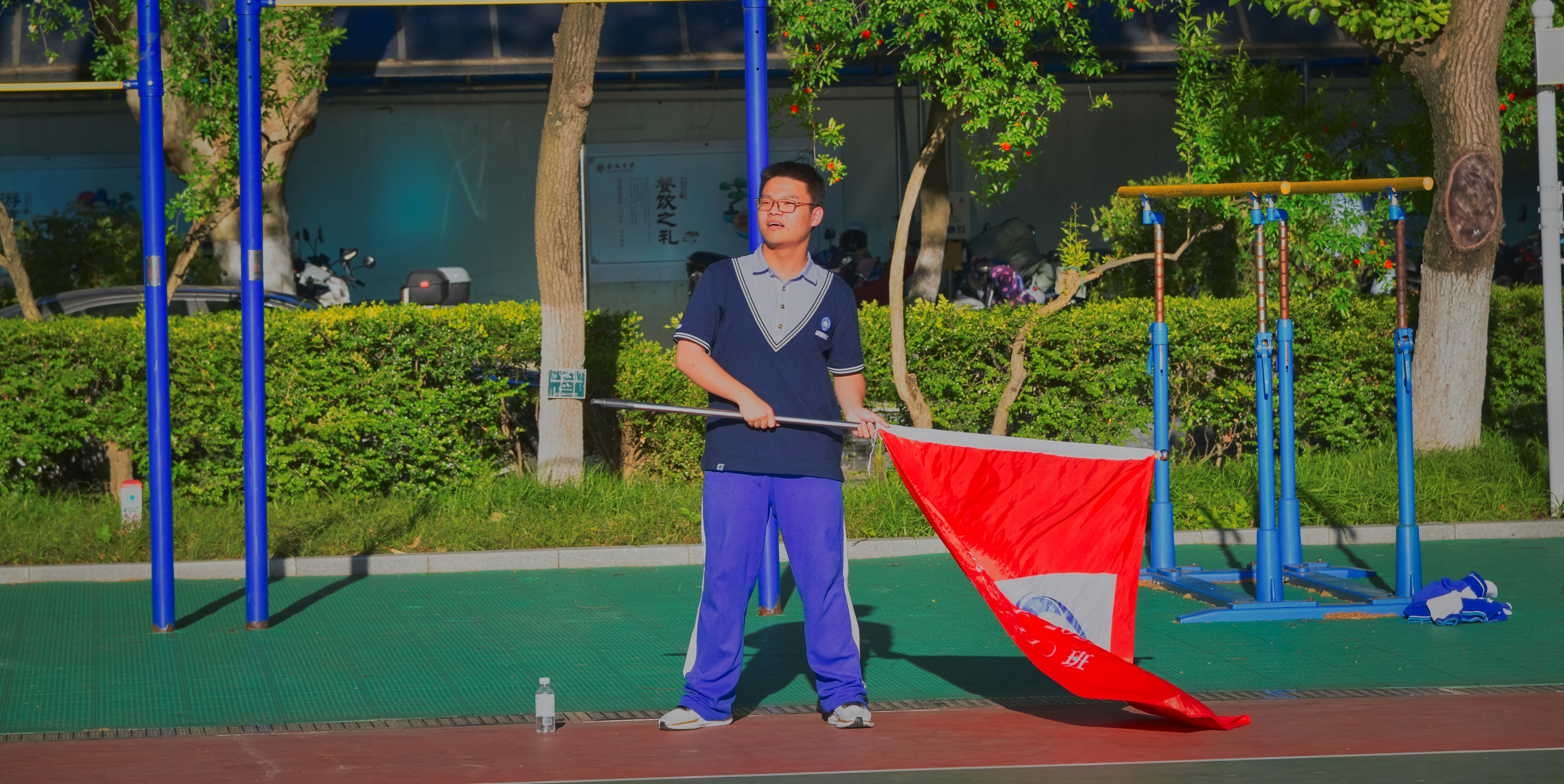 a man holding a red and white kite on top of a tennis court