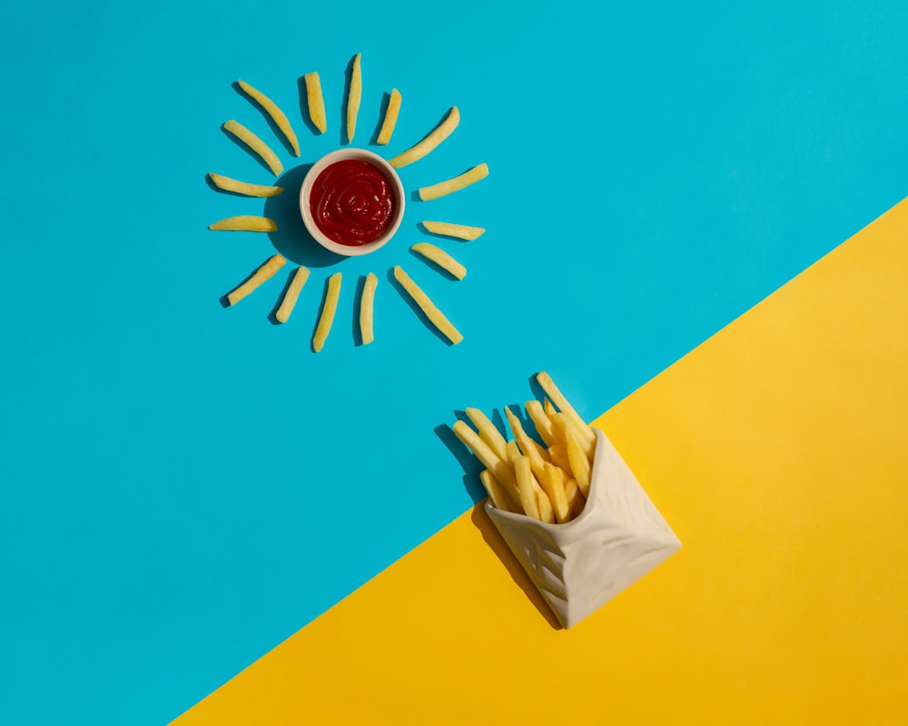french fries with ketchup in a paper bag on a blue and yellow background