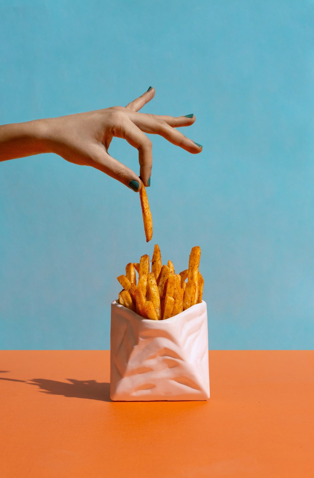 a hand reaching for a bag of french fries
