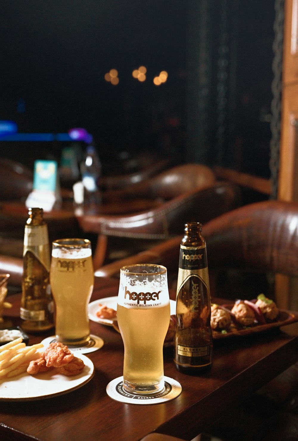 a wooden table topped with plates of food and glasses of beer