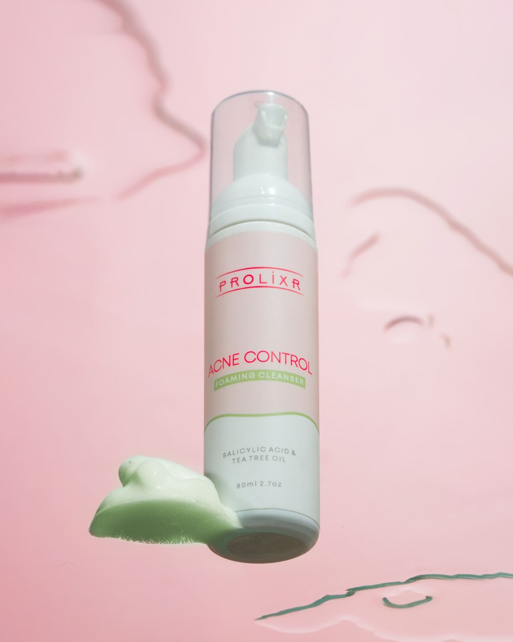 a close up of a bottle of lotion on a pink background