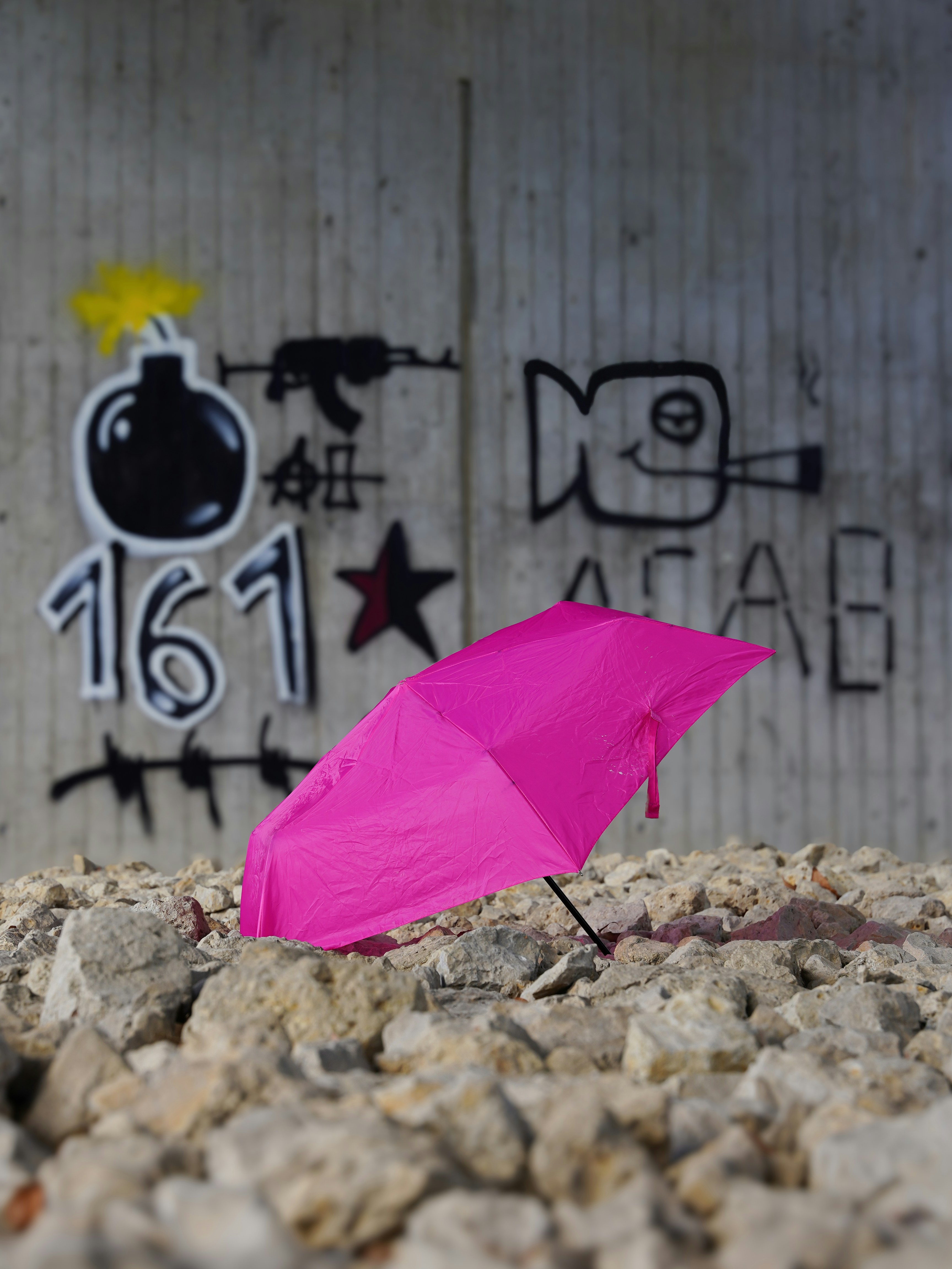 ein rosa Regenschirm, der auf einem Steinhaufen sitzt