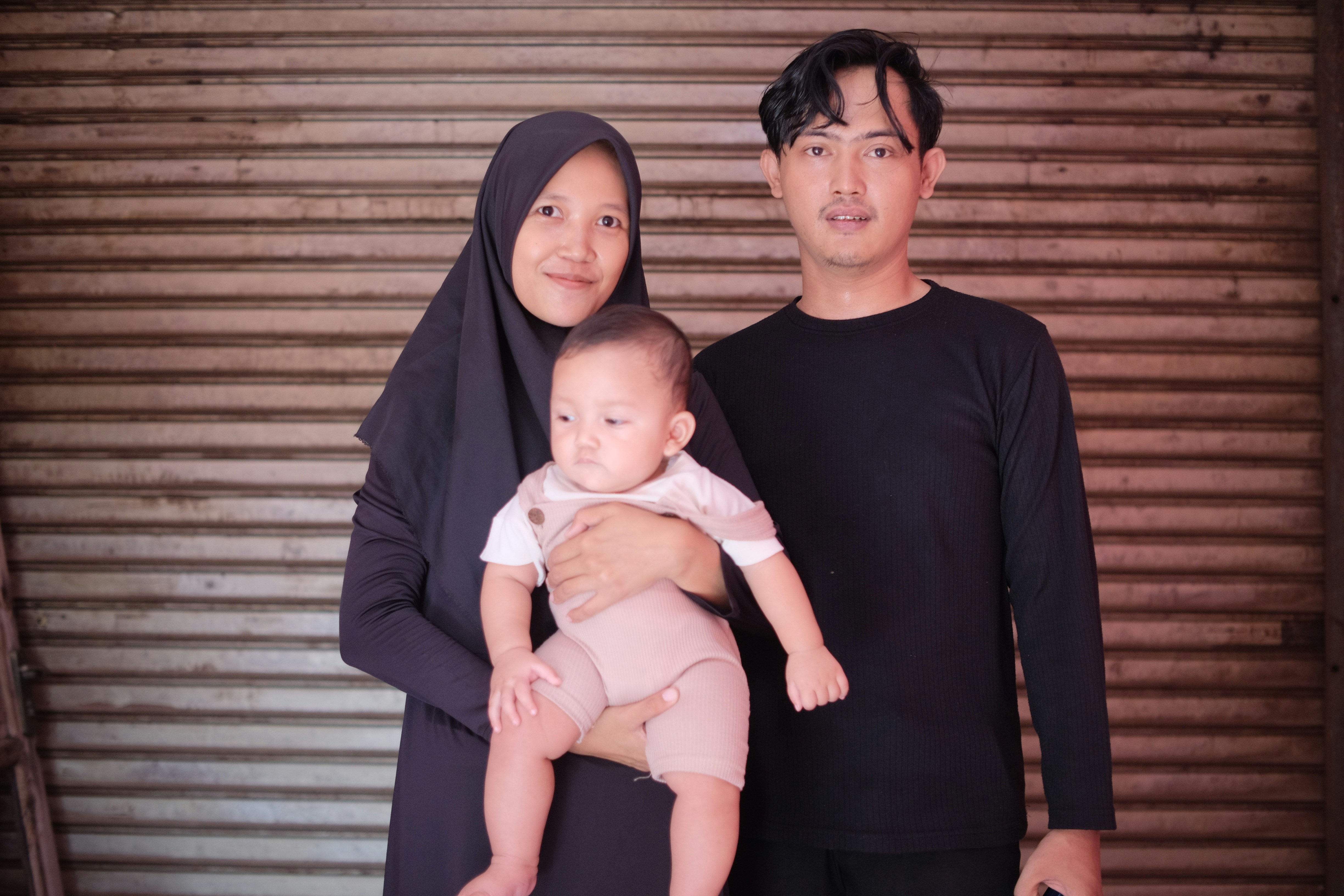 a man and a woman standing next to each other holding a baby