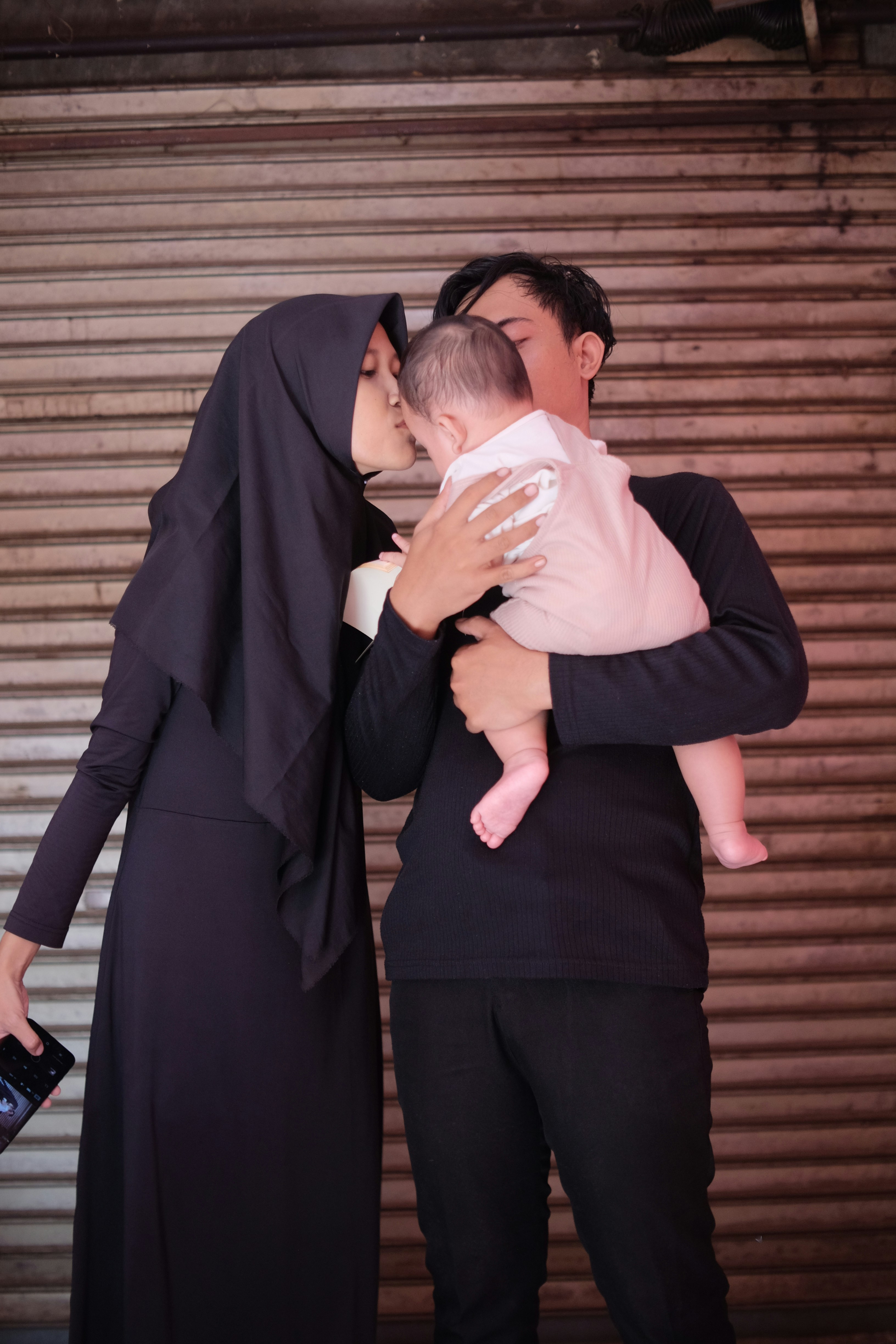 seorang wanita menggendong bayi sambil berdiri di samping seorang pria