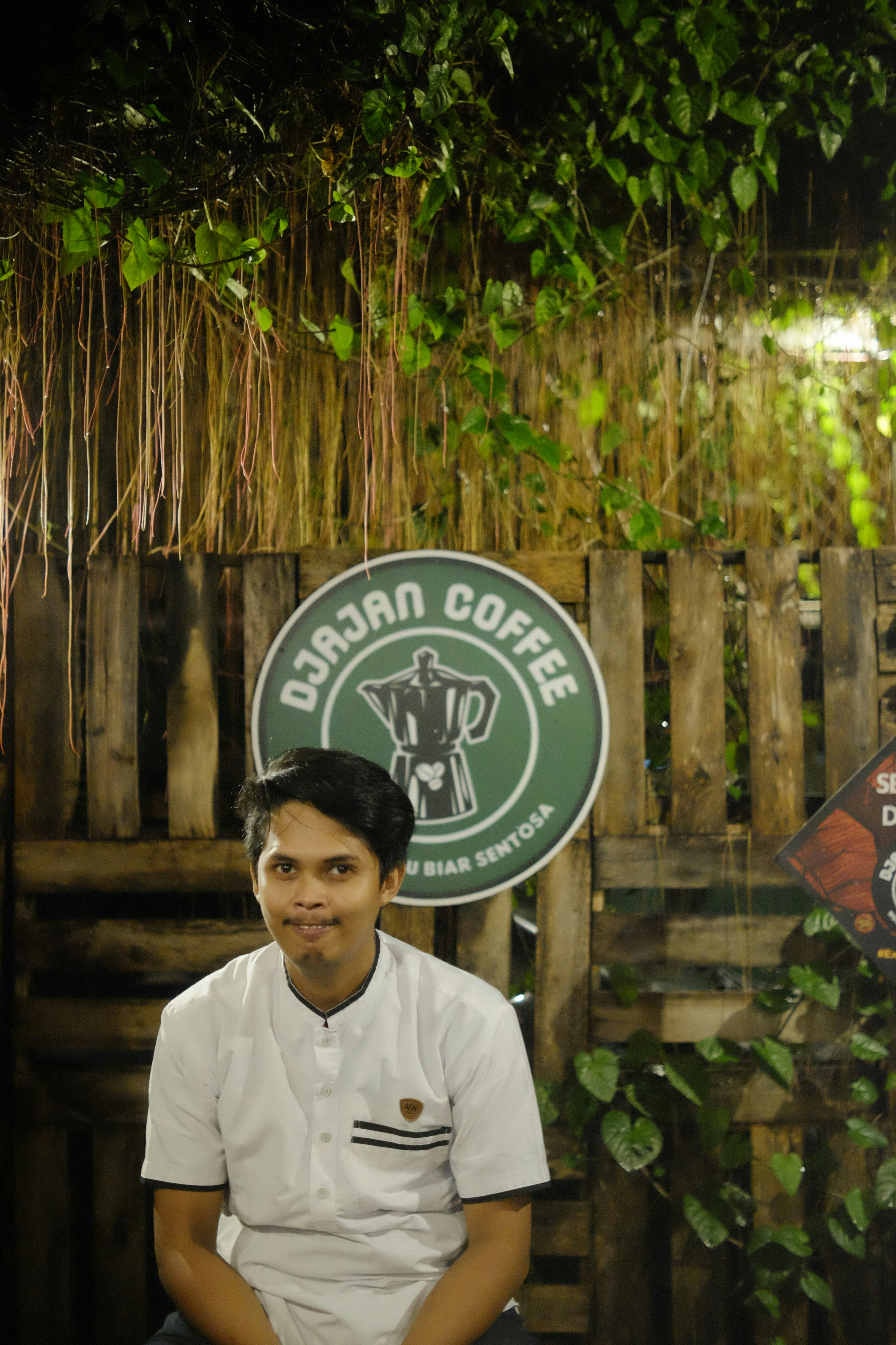 a man sitting in front of a wooden fence
