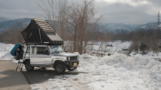 a jeep with a tent on top of it parked in the snow