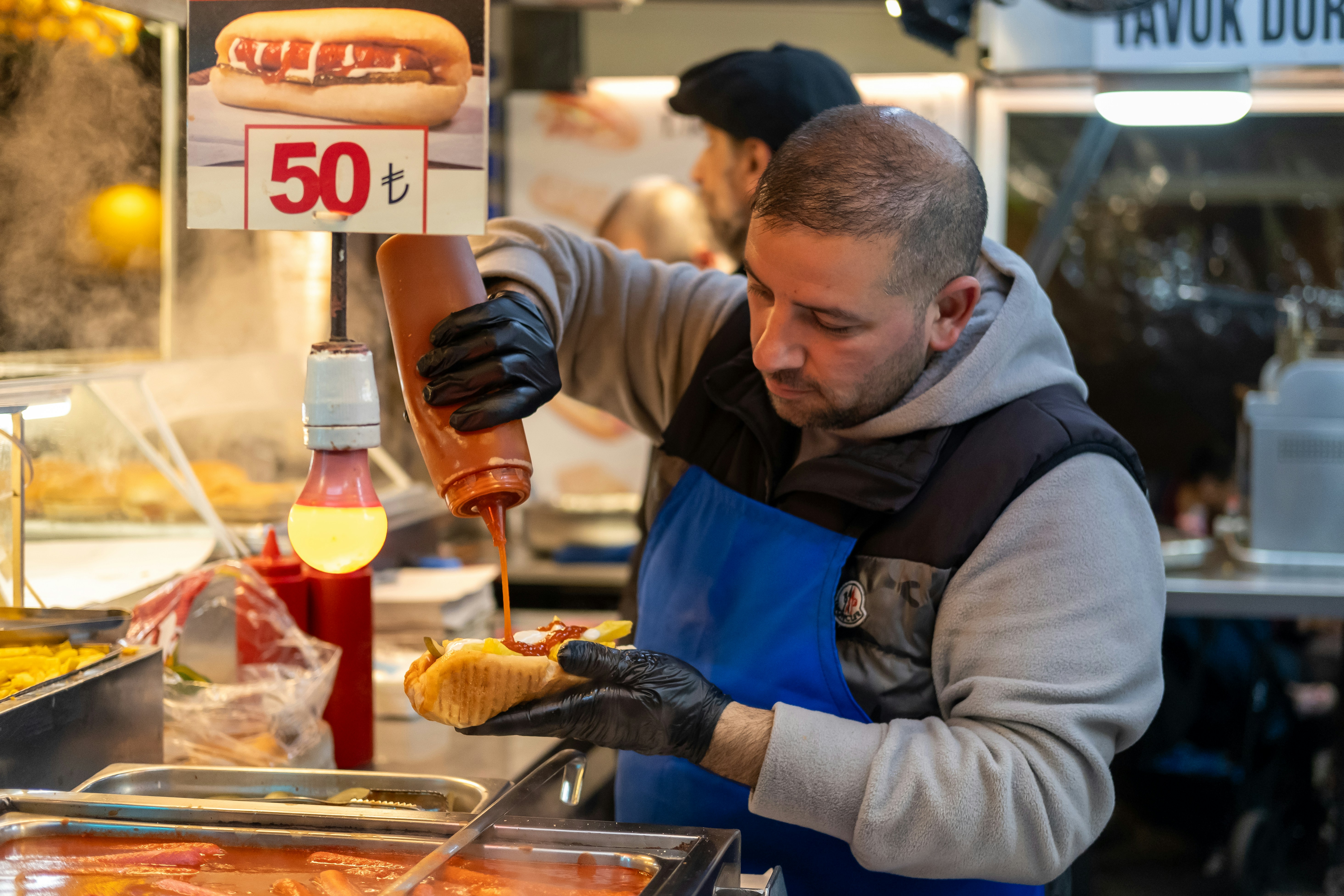 a man preparing food at a hot dog stand
