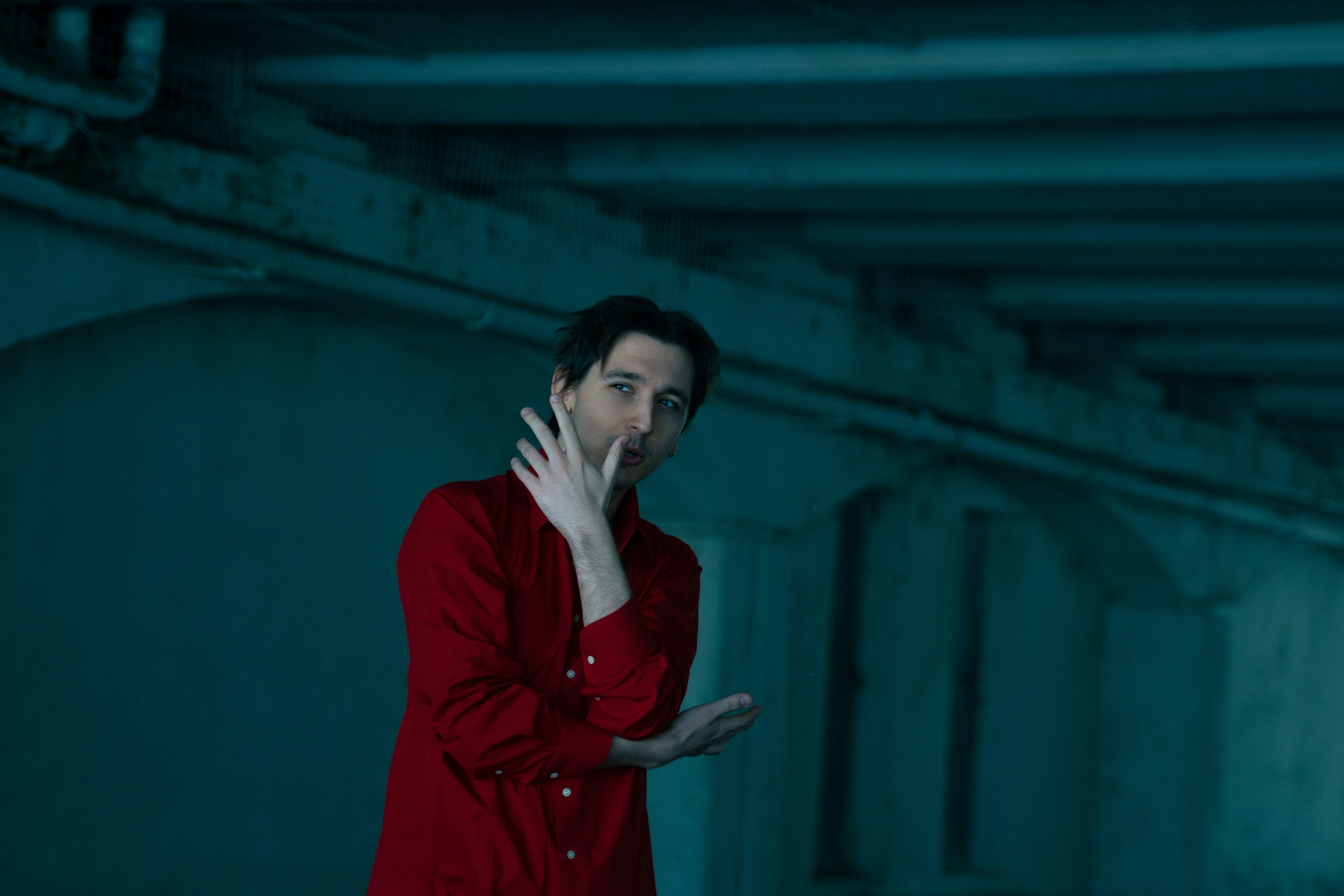a man in a red shirt holding his hand up to his face