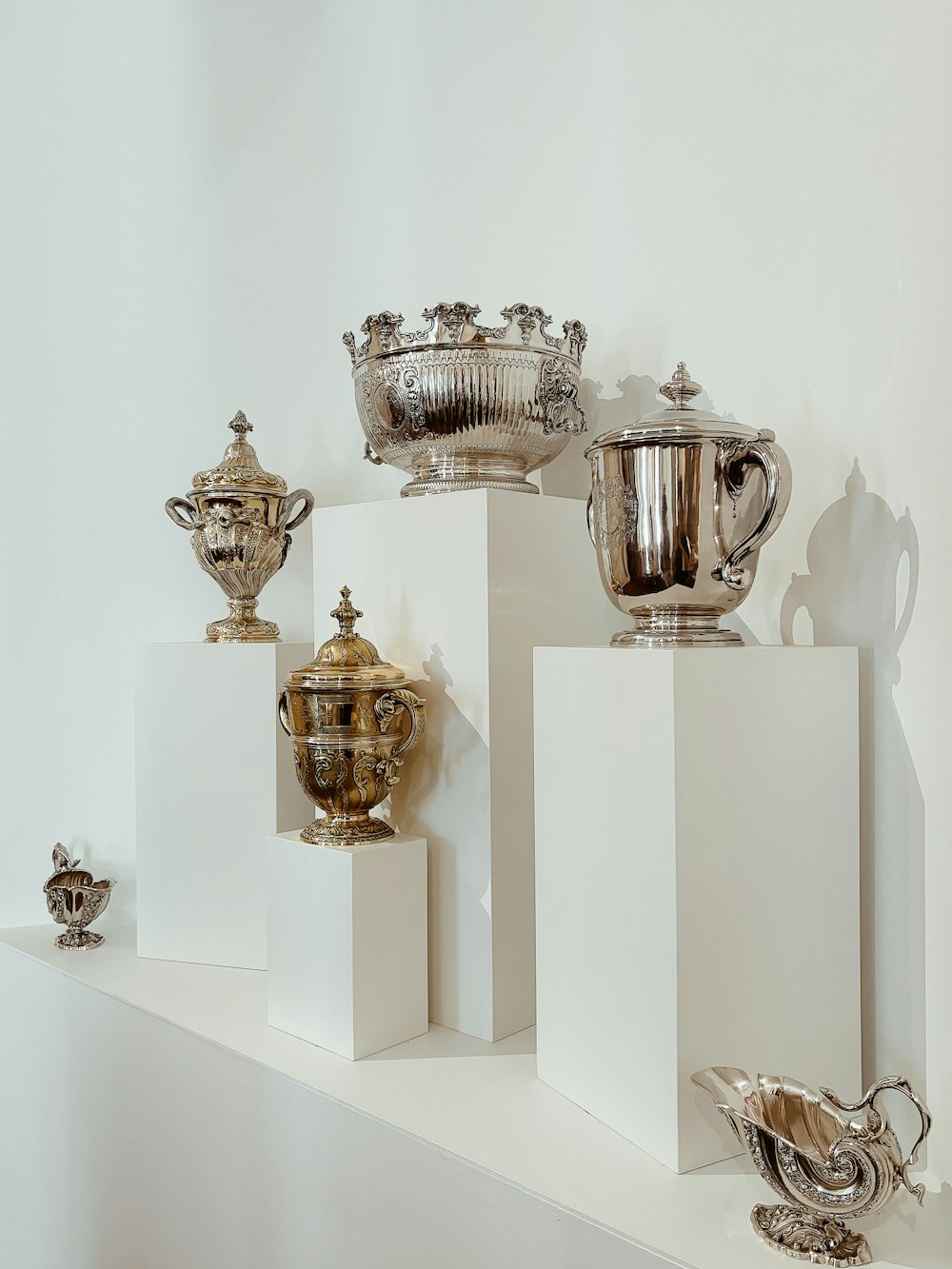 a white shelf topped with lots of silver vases