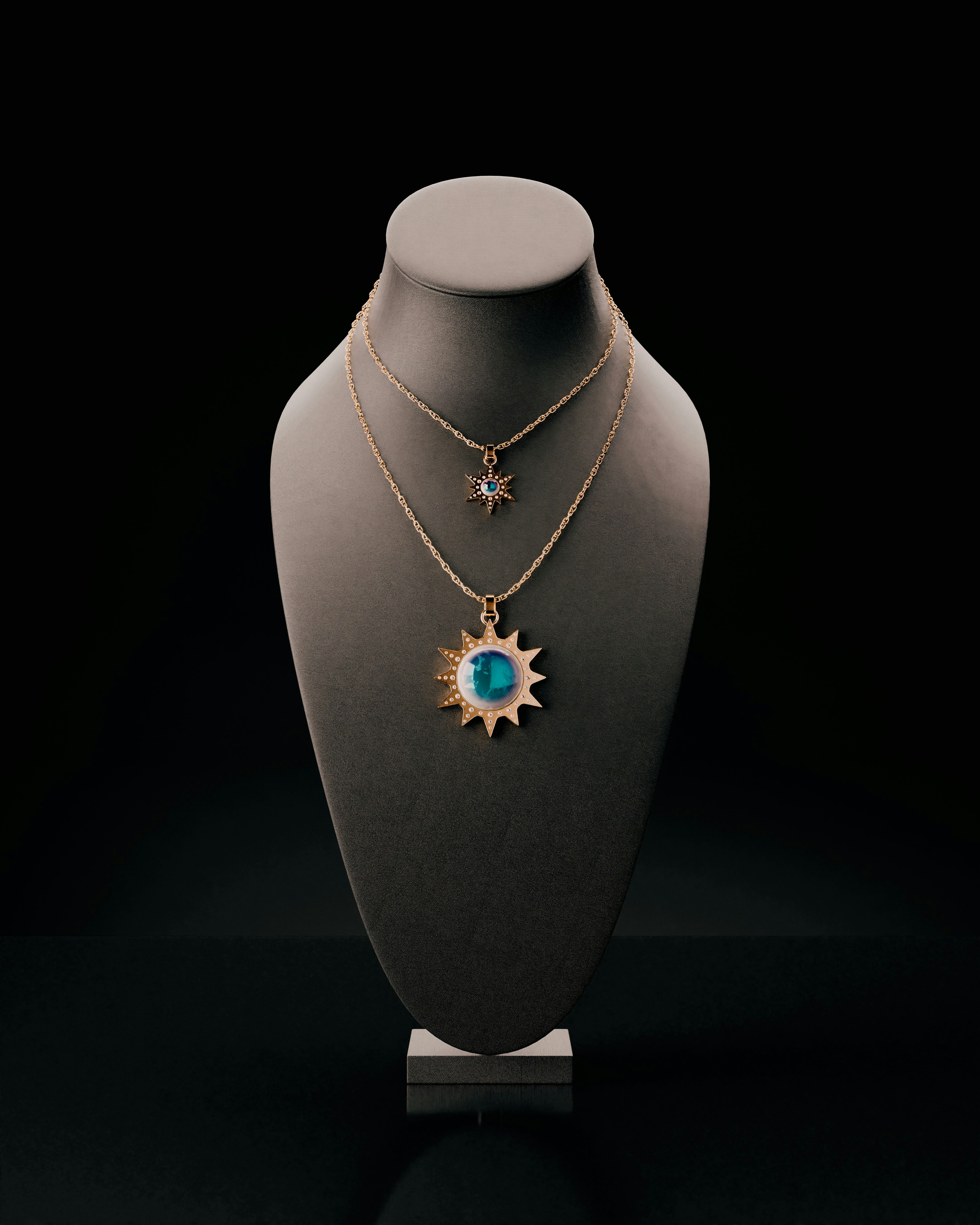 Two sun-shaped necklaces displayed on a bust.
