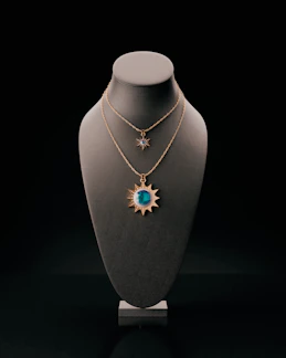 Two sun-shaped necklaces displayed on a bust.