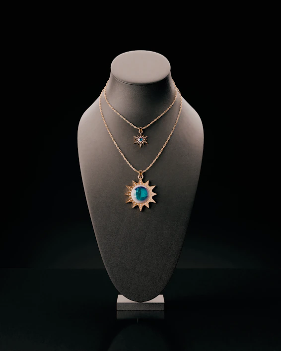 Two sun-shaped necklaces displayed on a bust.