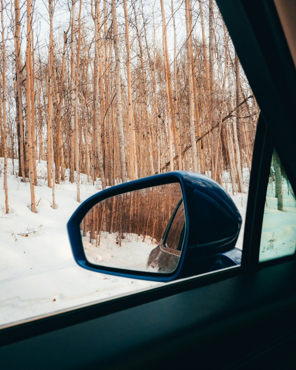 a car's side view mirror on a snowy road