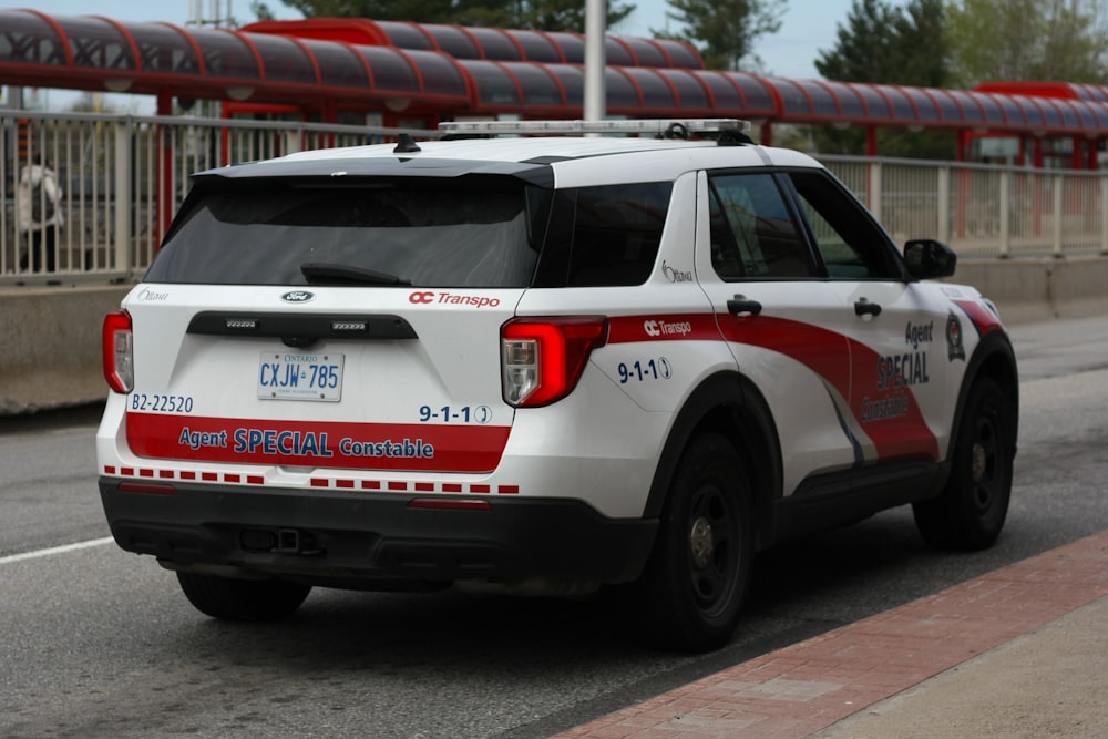 un coche de policía rojo y blanco conduciendo por una calle