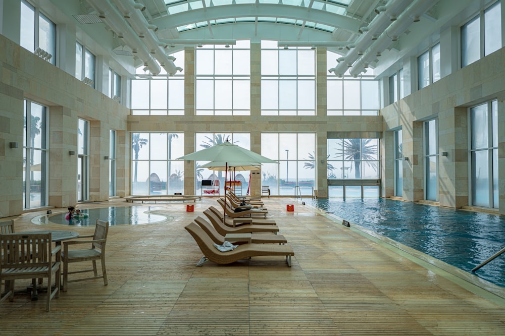 a large indoor swimming pool with lounge chairs and an umbrella