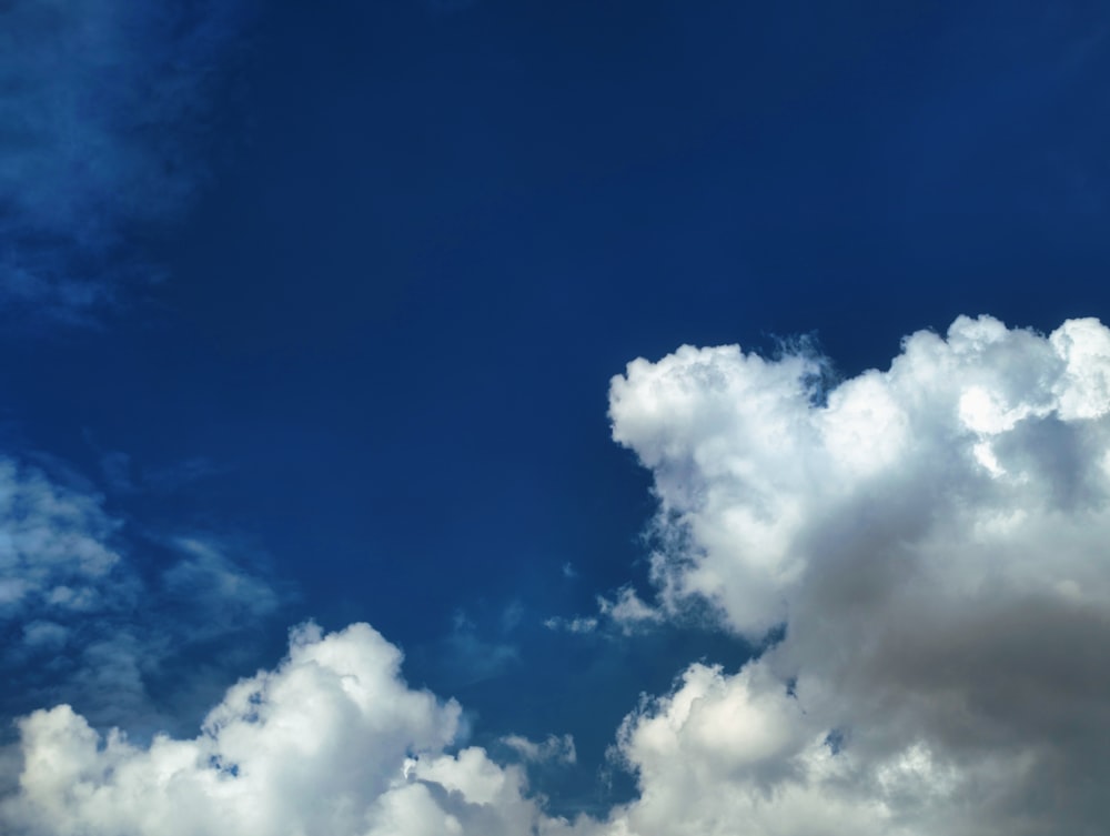 a plane flying through a blue cloudy sky