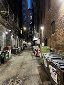a narrow alley with trash cans and garbage cans