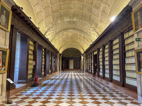 a long hallway with a checkered floor and paintings on the walls