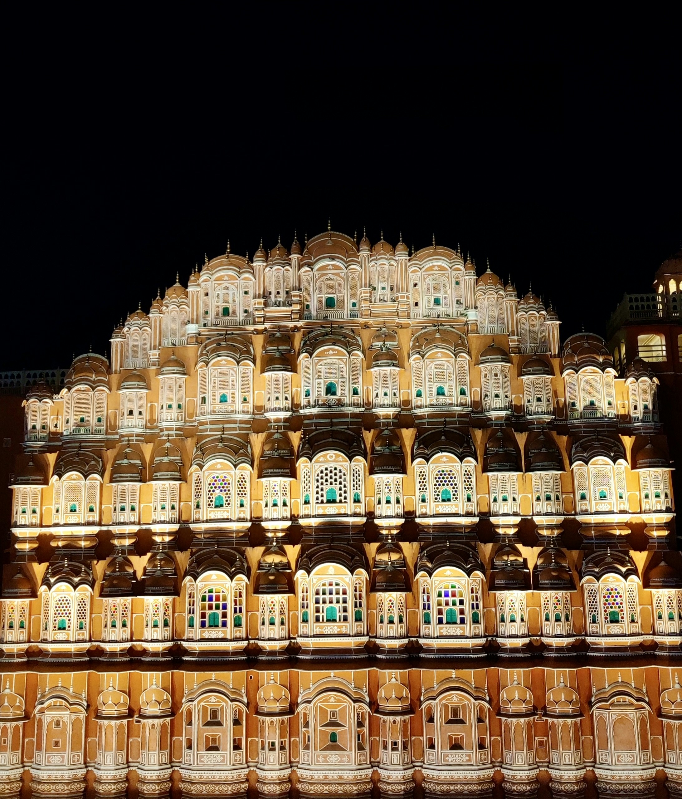 Palace at twilight with warm golden lights illuminating the façade, stars beginning to appear in the deep blue sky above